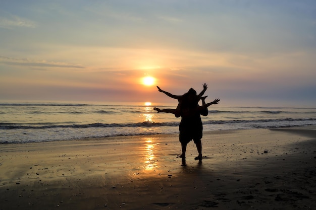 Silhouette of two women playing on the seashore at sunset Golden hour