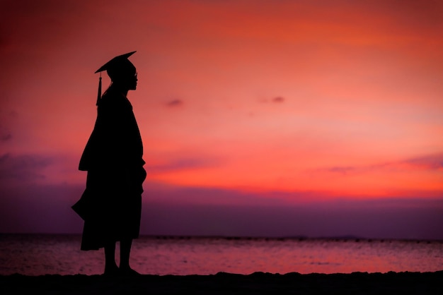 Silhouette of university graduated woman in sunset sky