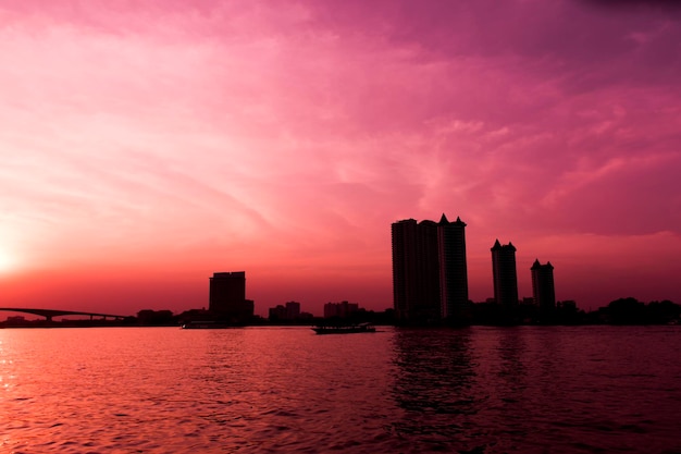 Silhouette of waterfront city and red sky