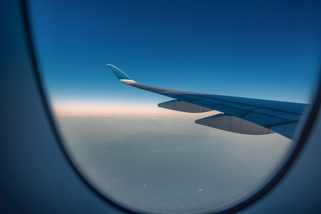 Silhouette wing of an airplane at sunrise view through the window.