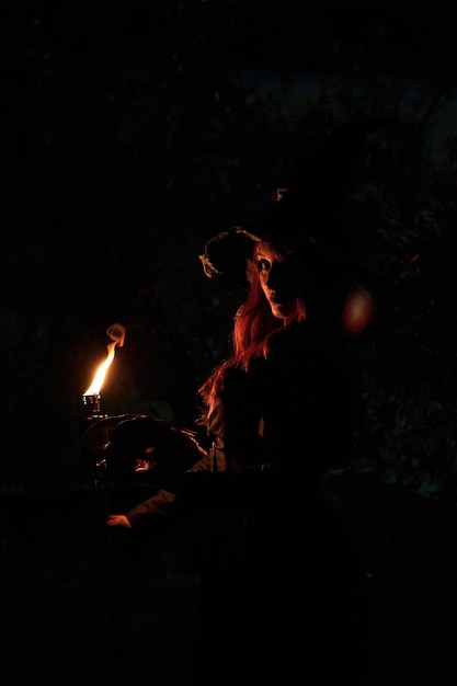 Silhouette of a witch woman with a torch and skull