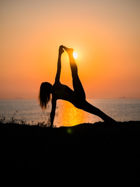 Photo silhouette woman doing yoga at beach against sky during sunset