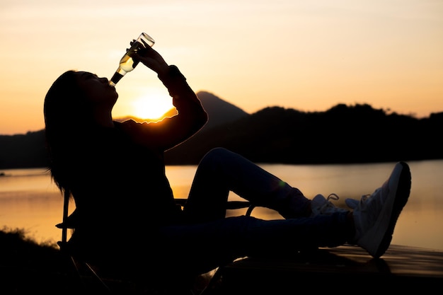 Silhouette woman drinking water on the beach at dusk