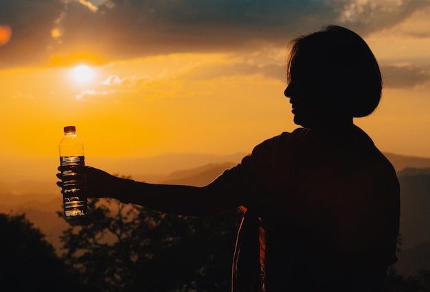 Silhouette of a woman drinking water drinking water in the sunset