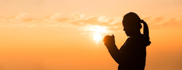 Silhouette of woman hand praying spirituality and religion female worship to god banner with copy space Religious people are humble to God Christians have hope faith and faith in god