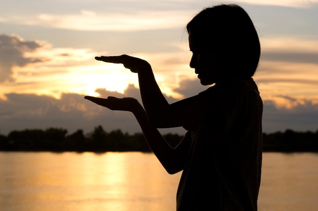 Silhouette of woman Hands with  beautiful sunset background.