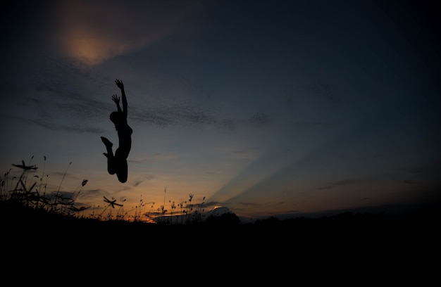 Silhouette woman jumping at sunset