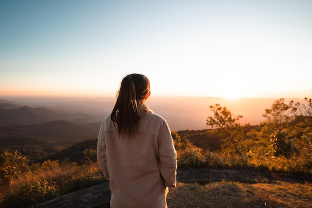 Silhouette woman looking at beautiful mountain valley in fog at sunrise in summer