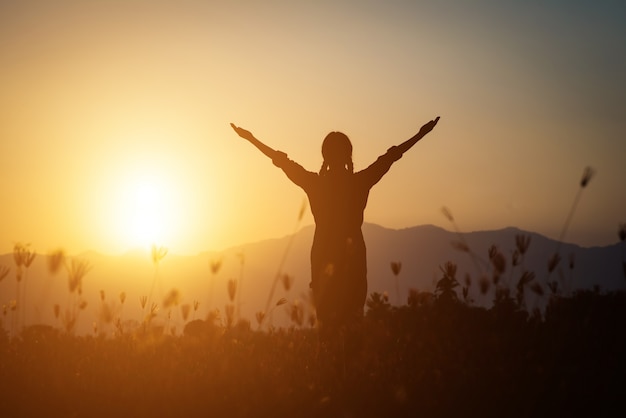 Silhouette of woman praying over beautiful sky background