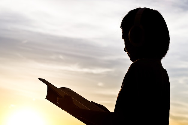 Silhouette of woman reading travel book.