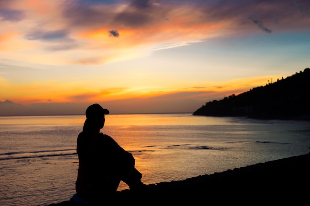 Silhouette of a woman sitting on a beach