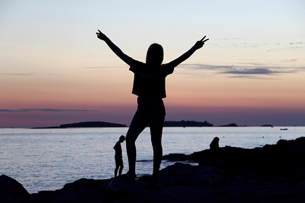 Photo silhouette woman standing on beach against sky during sunset