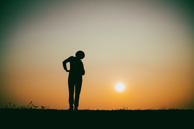 Silhouette of the woman standing lonely at the river during beautiful sunset