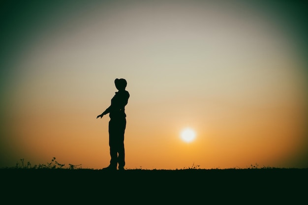 Silhouette of the woman standing lonely at the river during beautiful sunset