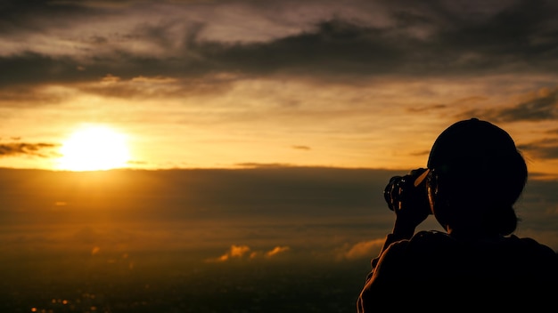 Silhouette of woman taking picture with camera at sunrise on DOI SUTHEP mountain viewpoint chiang mai Thailand