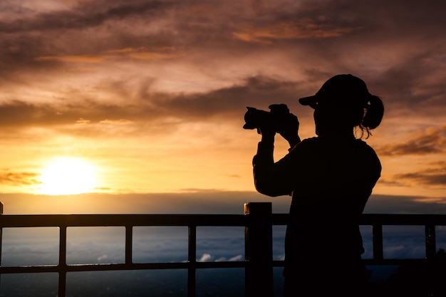 Silhouette of woman taking picture with camera at sunrise on DOI SUTHEP mountain viewpoint chiang mai Thailand