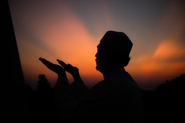 Silhouette Young asian muslim man praying on sunsetRamadan festival concept