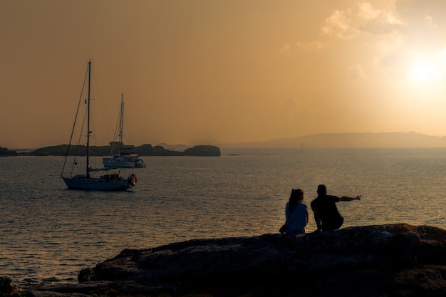 Silhouette of a young couple on the beach looking at the sea at sunset