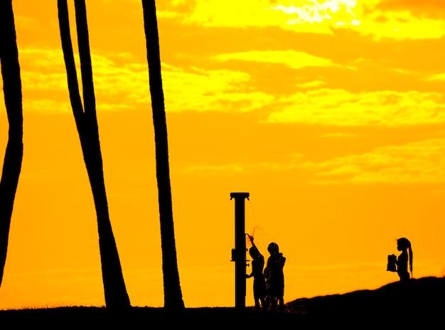 Silhouette of young kids on beach shower