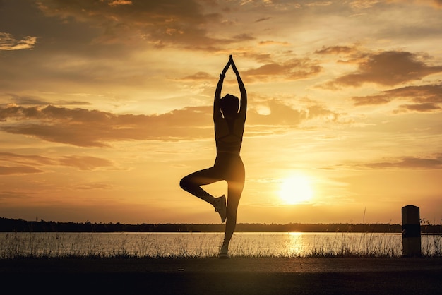 Silhouette Young woman practicing Meditation yoga onÃÂÃÂ the beach at sunset