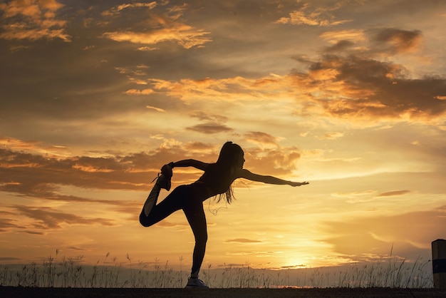 Silhouette Young woman practicing Meditation yoga onÃÂÃÂ the beach at sunset