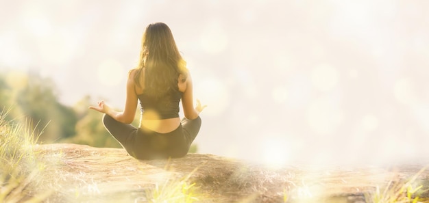 Silhouette young woman practicing yoga on top of the mountain copy space