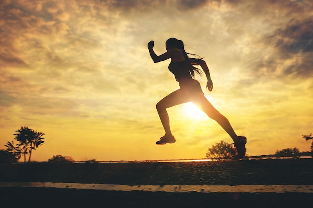 Silhouette of young woman running sprinting on road Fit runner fitness runner outdoor workout