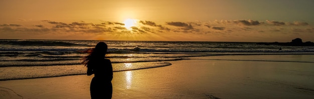 Silhouette of a young woman watching the sunset on the beach