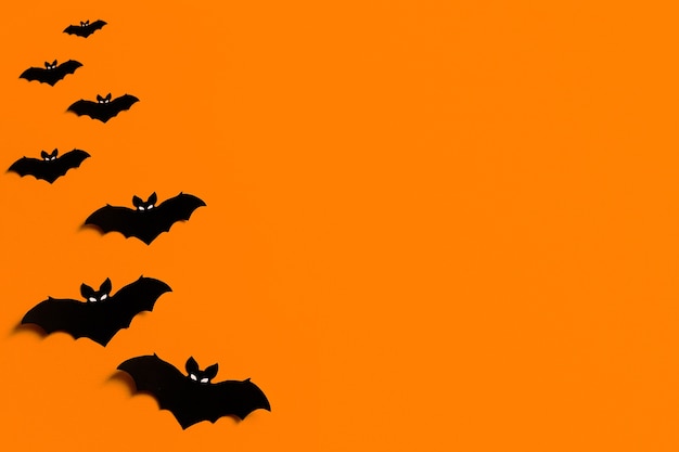 Silhouettes of black paper bats on an orange background for Halloween