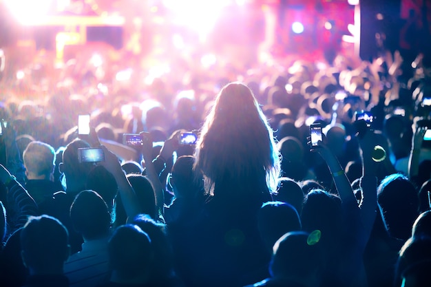 The silhouettes of concert crowd in front of bright stage lights. Concert of an abstract rock band