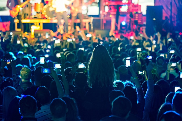 The silhouettes of concert crowd in front of bright stage lights. Concert of an abstract rock band