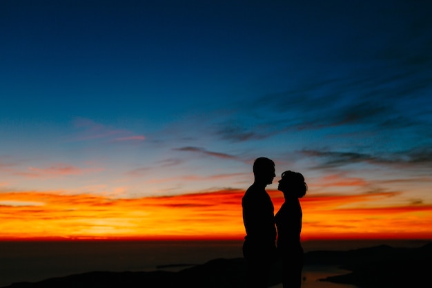 Silhouettes of a couple against the sunset in the mountains close up