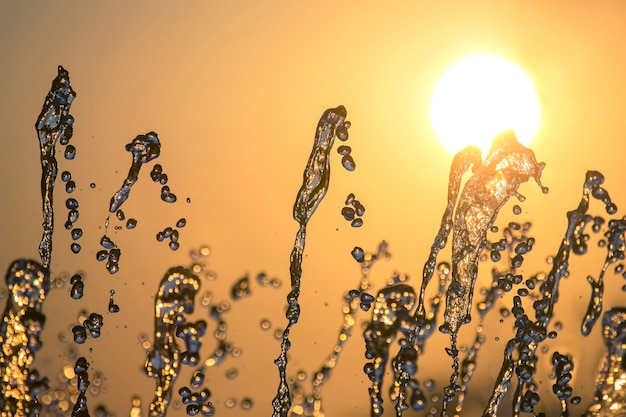 Silhouettes of drops falling water fountain against the backdrop of the setting sun