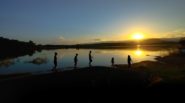 Silhouettes of fishing boys and girl are walking home after fishing the lake in the evening sun, Reservoir Amphoe Wang Saphung Loei Thailand