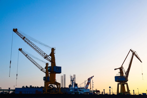 Silhouettes of harbor cranes at sunset Shipyard at sunset