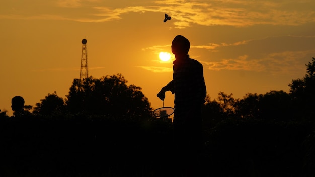 Silhouettes Man is holding the shuttlecock and the badminton racket