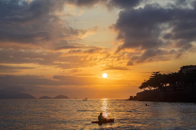 Silhouettes of people in canoes at dawn on Copacabana beach in Rio de Janeiro