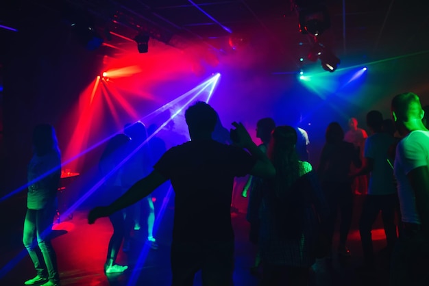 Silhouettes of people dancing in nightclub on dance floor at party