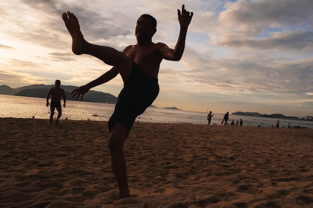 Silhouettes of Vietnamese men playing beach soccer in the morning by sea at sunrise in Nha Trang Nha Trang Vietnam July 19 2024