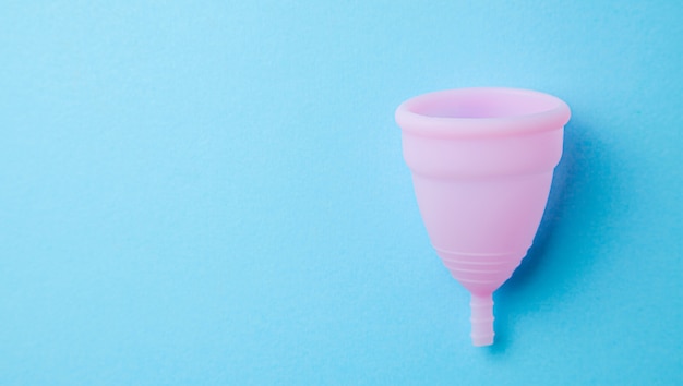 Silicone menstrual cup. Women's health and alternative hygiene. Blue background.