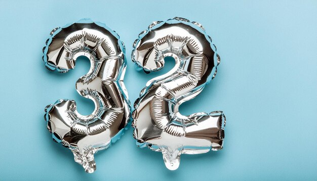 Photo silver balloon number 32 over isolated blue backdrop birthday celebration anniversary card