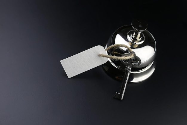 Silver bell and the key at the reception in the hotel on a black background