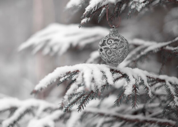 Photo silver christmas ball on a natural tree in a snowy forest