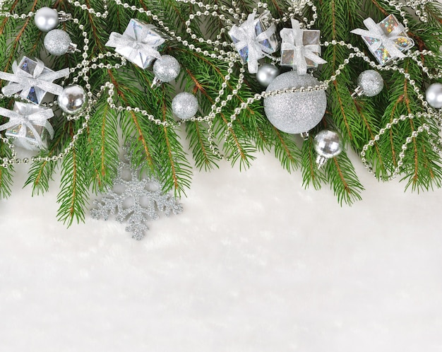 Silver Christmas decorations on a spruce branch on a white background