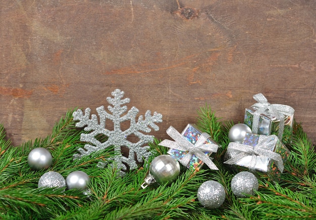 Silver Christmas decorations and spruce branch on a wooden background