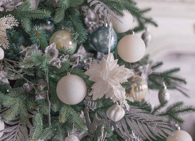 Silver Christmas ornaments hanging on fir tree.section of a Christmas tree laden with pastel and expensive ornaments