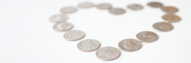 Silver coins lying in shape of heart on white background. Love of money concept