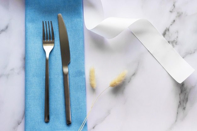 Silver cutlery on the blue linen napkin with dried flowers decor Table decoration set