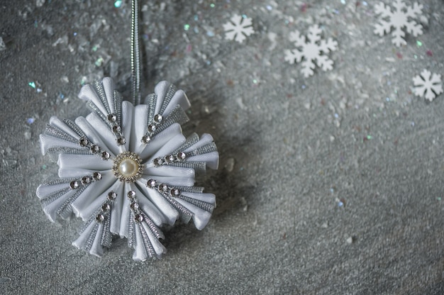 Silver decorative snowflakes on a silver background with snow