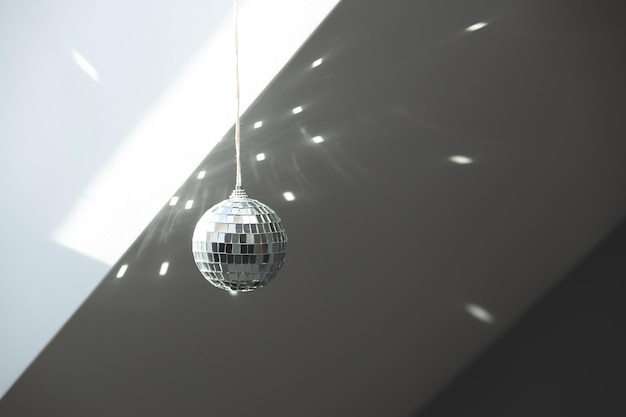 Silver disco ball reflects sunlight on gray background